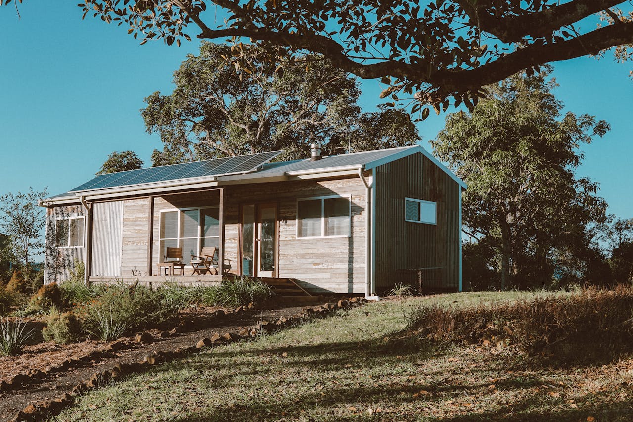A charming wooden house in Australia featuring solar panels, surrounded by lush greenery.